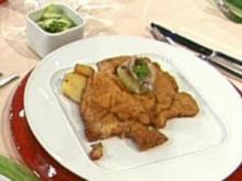 Wiener Schnitzel auf der Manschette serviert mit Röstkartoffeln und Gurkensalat a la Buchholz - Rezept