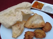 Pakoras und Samosas, dazu Pickles, Chutney, Minzsoße und Papadam - Rezept
