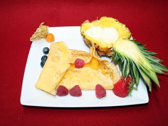 Crêpes mit Orangenlikörsoße,  Vanilleeis und Früchten - Rezept