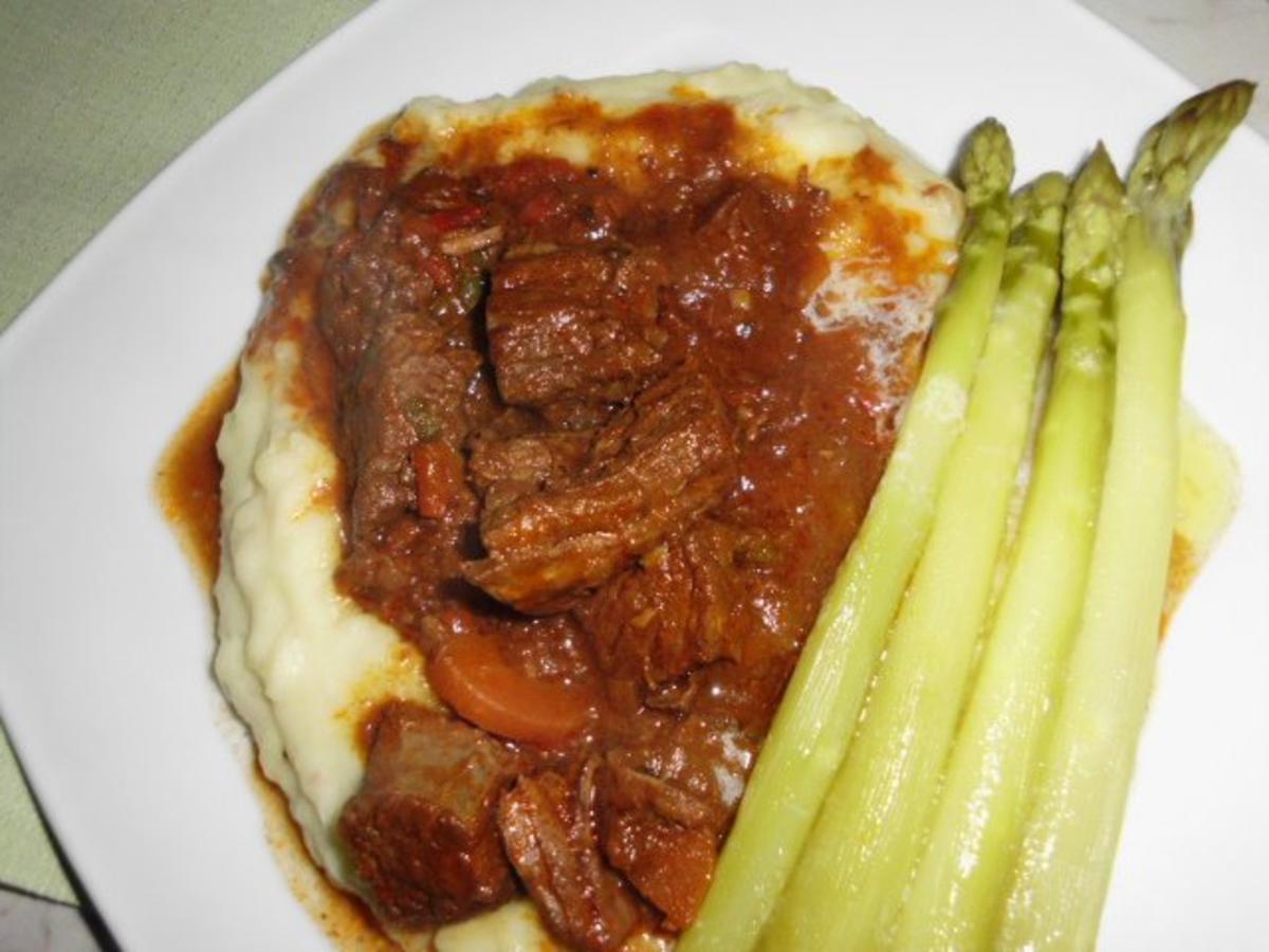 Rindergulasch auf Kartoffelpüree, mit Butter übergossener grüner ...