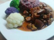 Seitan-Pilz-Gulasch an lila Kartoffelbrei mit orangen Tupfen und bunten Röschen - Rezept