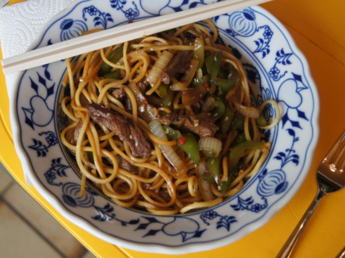 Chinesische Nudeln im Wok mit Rindfleisch. Paprika und Zwiebeln ...