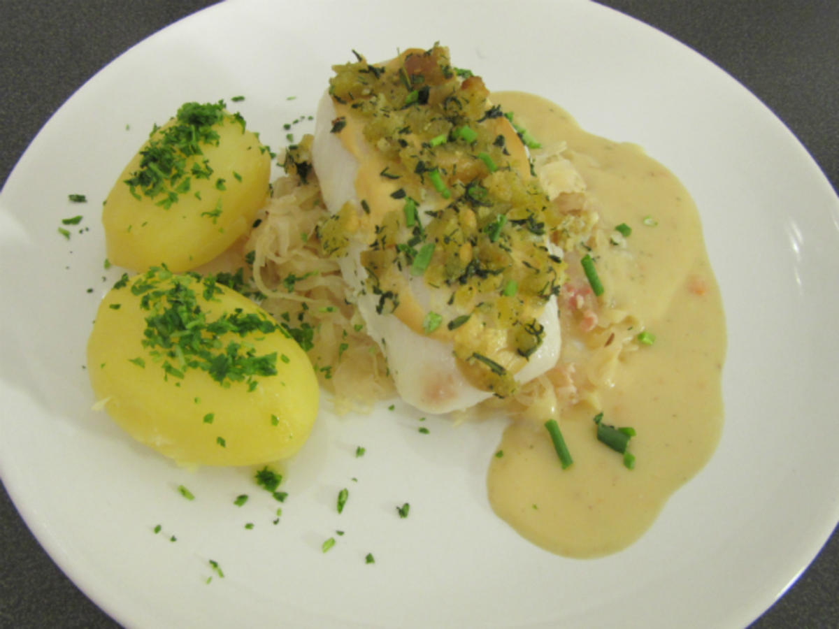 Bio-Kabeljaufilet mit einer Kräuterkruste an Sauerkraut auf ...