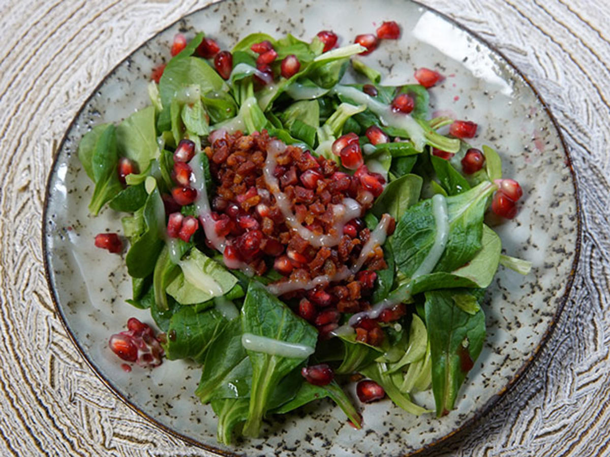 Feldsalat mit Granatapfelkernen und Speckwürfeln an Kartoffeldressing ...