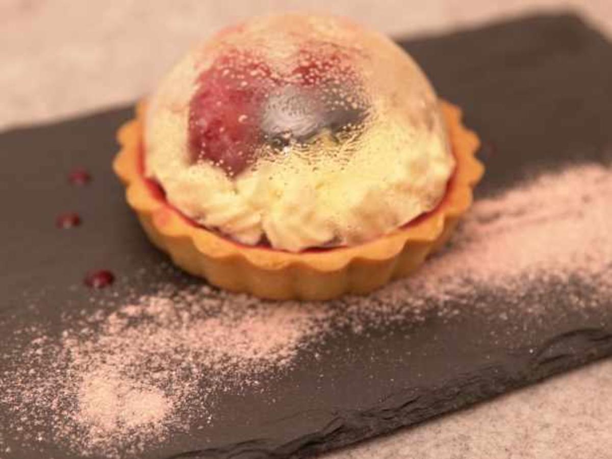 Tarte mit Himbeerspiegel, weißem Schokoladenfrosting und Zuckerdom ...