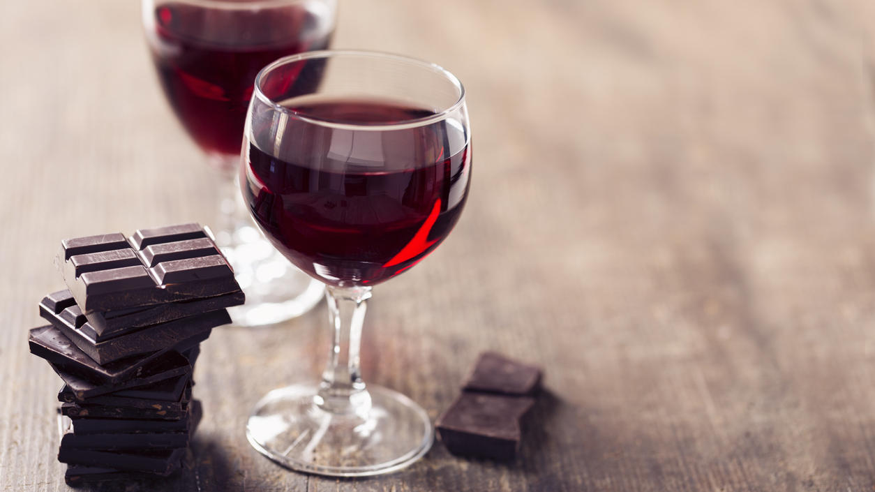 Sirtfood-Diät: Abnehmen mit Wein und Schokolade – funktioniert das? Zwei Gläser Rotwein mit Zartbitterschokolade.