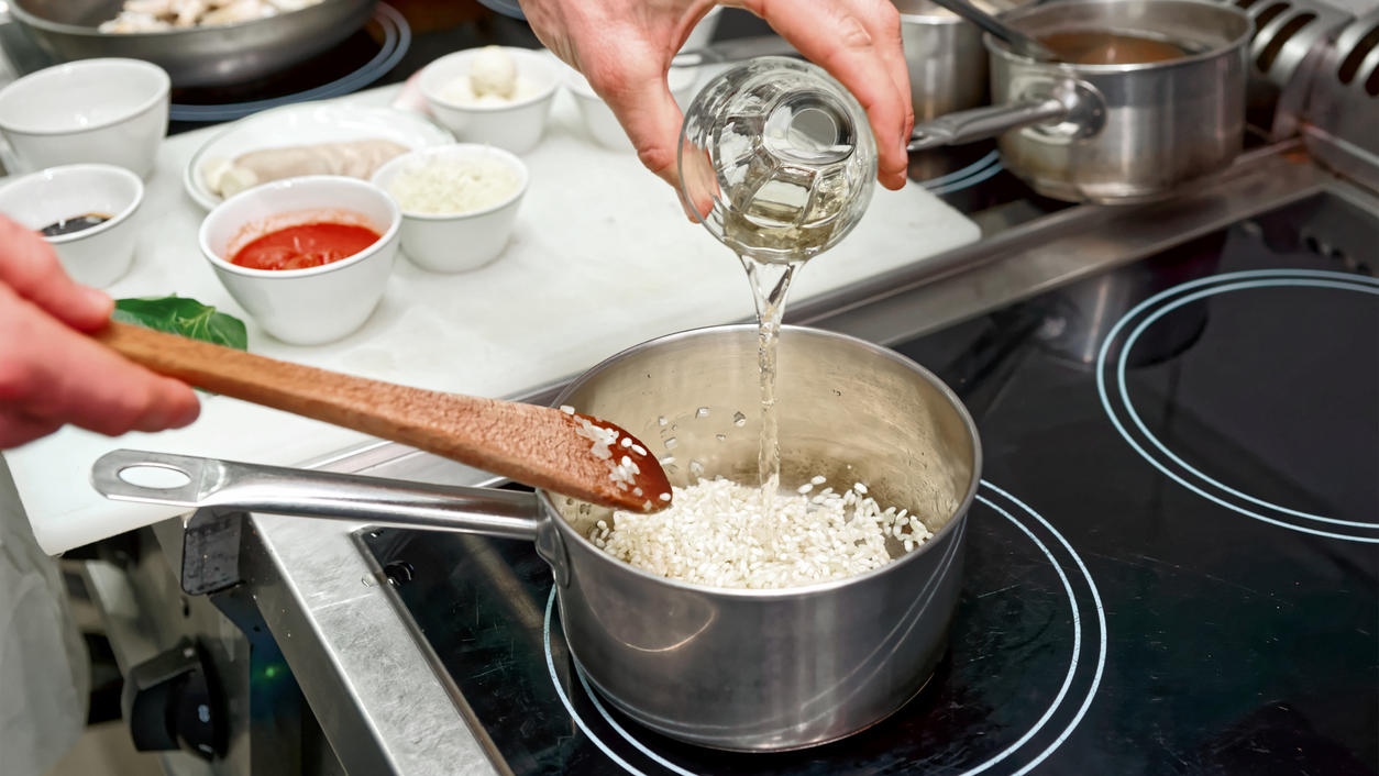 Gerichte mit Schuss: Alkohol verdunstet nicht vollständig beim Kochen Koch fügt Weißwein zum Risotto hinzu