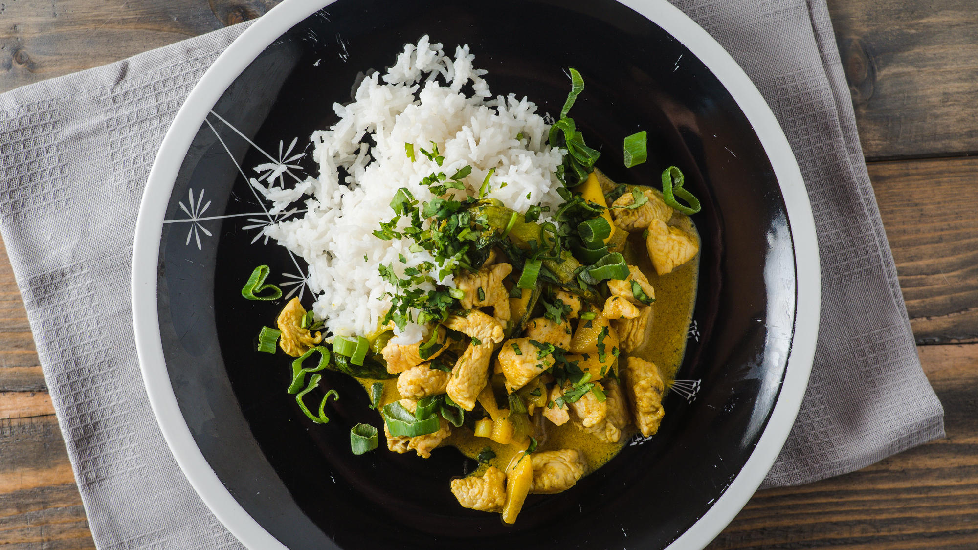 Blitzgericht: Mildes Süßkartoffel-Kokos-Curry Delicious turkey mango curry with rice on a black plate