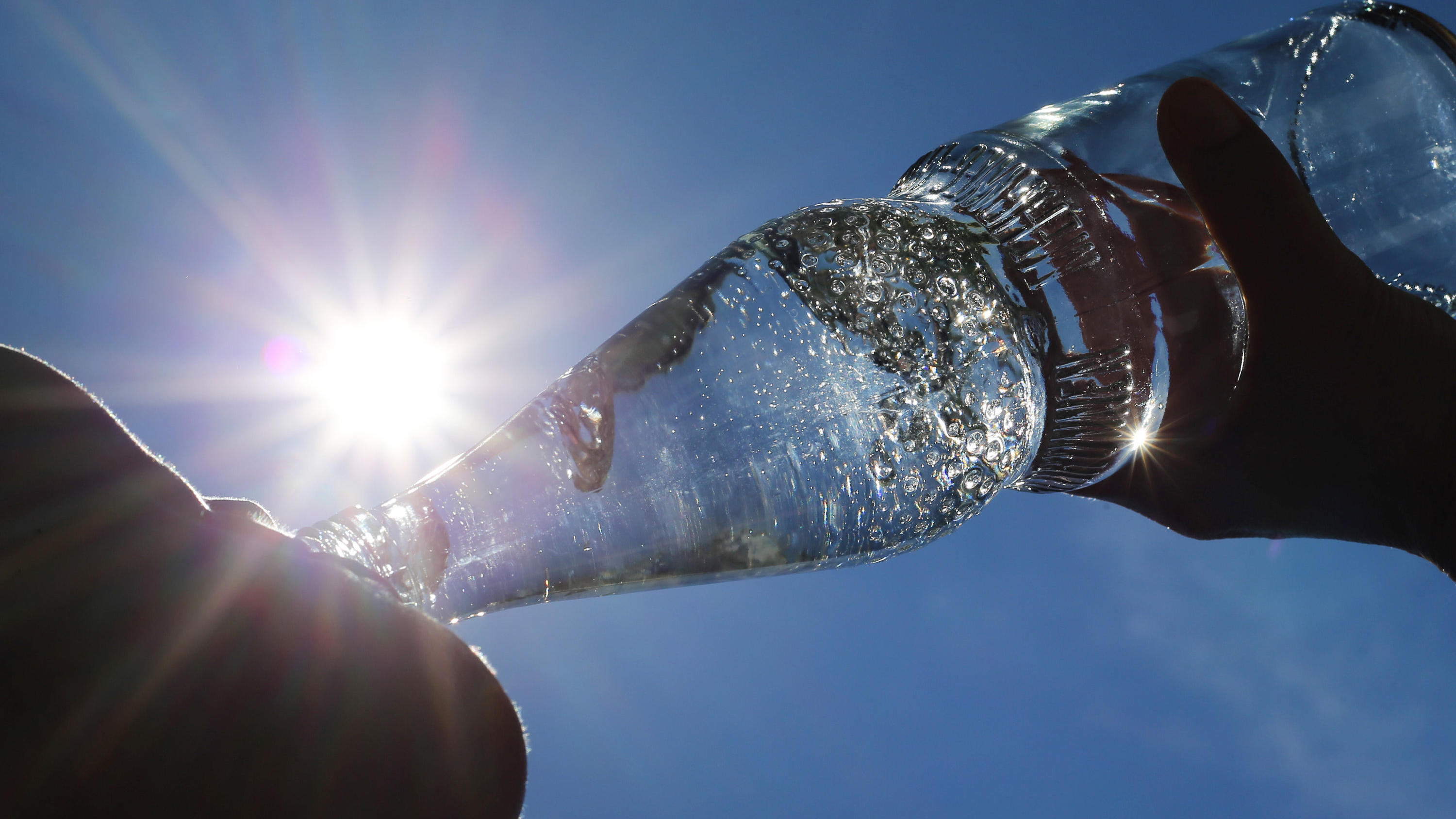 Bier, Wein & Co: Was darf ins Gefrierfach – und wie lang? ARCHIV - 24.06.2019, Bayern, Kempten: Eine Frau trinkt im Sonnenschein aus einer Flasche sprudelndes Mineralwasser. (zu dpa: "Sex-Lust, Pickel und kalte Limo: Hitze-Mythen auf dem Prüfstand") Foto: Karl-Josef Hildenbrand/dpa +++ dpa-Bildfunk +++