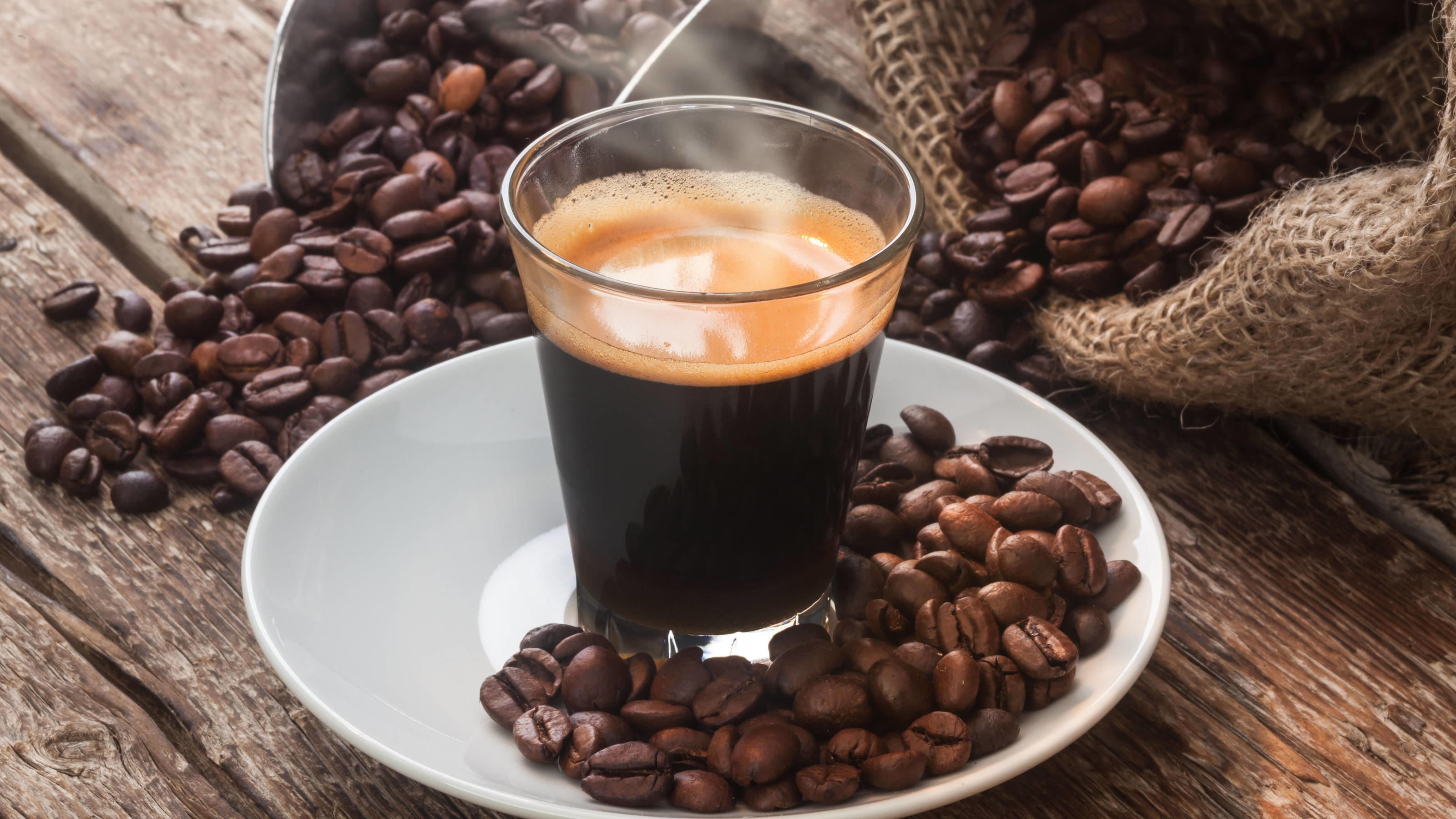 Ganze Kaffeebohnen im Test: Welche schmecken am besten? Frisch gebrühter Kaffee vor Kaffeebohnen