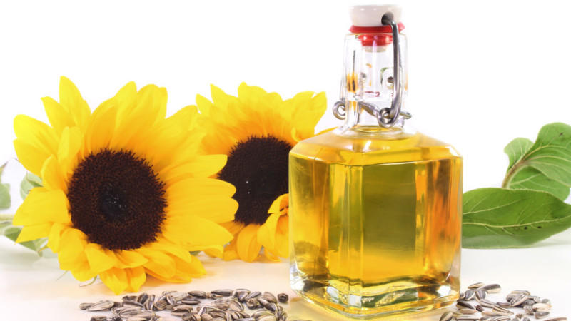 Eine Flasche Sonnenblumenöl mit Sonnenblumen