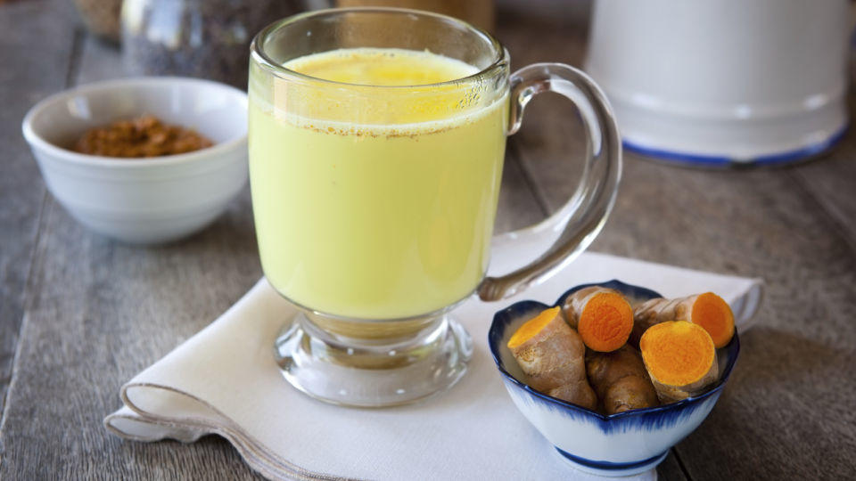 Kurkuma Latte: Die 'Goldene Milch' ist das Trendgetränk im Herbst Golden milk. Turmeric herbal medicine, an anti-inflammatory. Shallow DOF, focus on the brim of the glass and the foam on milk
