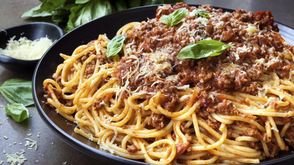 Diese Spaghetti schmecken am besten Spaghetti bolognese in black serving platter, with fresh basil and parmesan.
