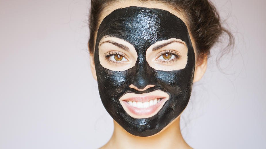 Schwarze Smoothies sind DER Detox-Trend: Mit Aktivkohle entgiften Eine junge Frau hat eine Gesichtsmaske mit Aktivkohle aufgetragen.
